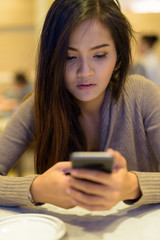 Young beautiful Asian woman sitting inside the restaurant