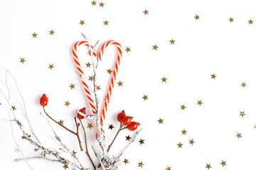 Christmas composition. Red rosehip berries on a white background and golden stars. Christmas, new year, winter concept. Flat lay, top view, copy space