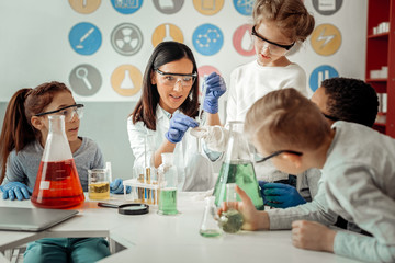 Competent young scientist teaching her delighted pupils