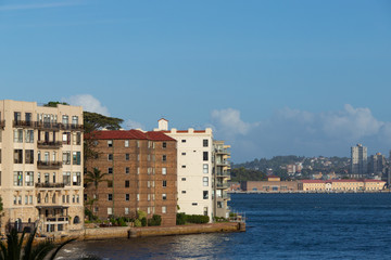 Obraz premium Apartment buildings by the water with clear blue sky.