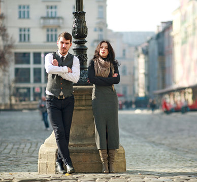 Young couple of actors in classic style clothing take part in scene of concept relationship on town street