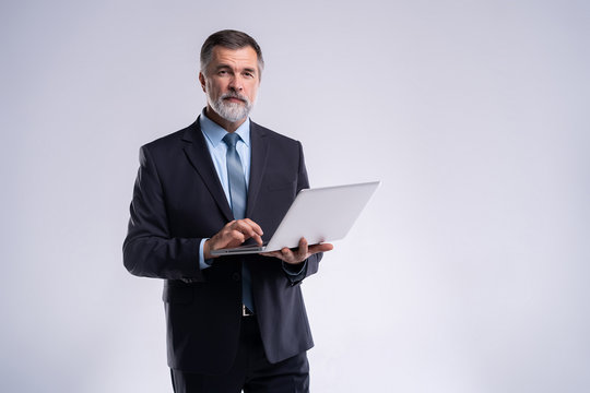 Always Ready To Help You. Confident Mature Man In Formalwear Holding Laptop And Smiling While Standing Isolated On White Background