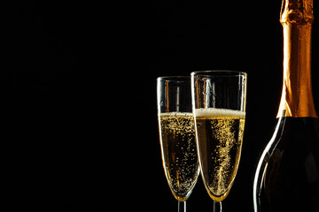 bottle of champagne and glasses over dark background