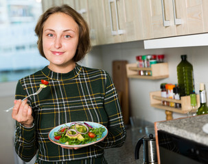 Woman standing with salad at kitchen