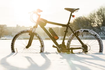 Foto auf Acrylglas Fahrräder Radfahren in der Wintersaison. Schwarzes Fahrrad auf dem Schnee im Stadtzentrum. Sport zu jeder Jahreszeit Konzept.