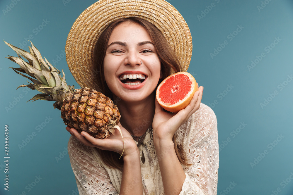 Sticker Cute pretty woman posing isolated over blue wall background with pineapple.