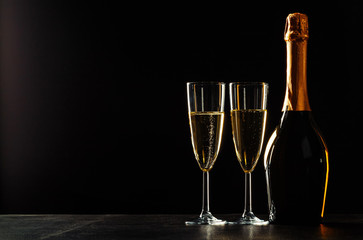 bottle of champagne and glasses over dark background