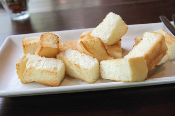 Sliced baguette bread in a plate on a wooden table