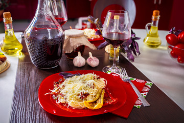 Delicious spaghetti with cheese and dried tomatoes served on a red plate