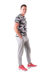 Fototapeta premium Confident happy handsome young adult man in sportswear with hands in pockets. Full body isolated on white background. 