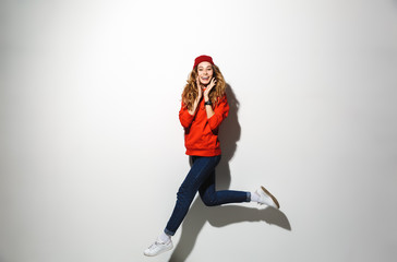 Fototapeta na wymiar Full length portrait of an excited girl wearing hoodie jumping