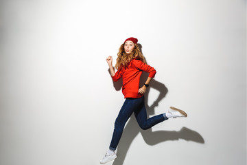 Full length portrait of an excited girl wearing hoodie jumping