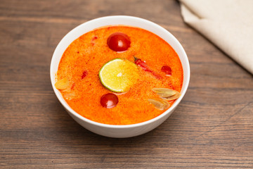 Tom Yum Kung-Thai spicy shrimp soup in white bowl on wooden table