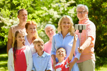 generation and people concept - happy family taking picture with smartphone and selfie stick in summer garden