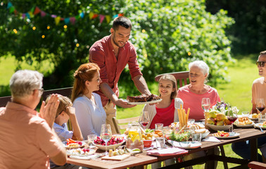 leisure, holidays and people concept - happy family having festive dinner or barbecue party at summer garden