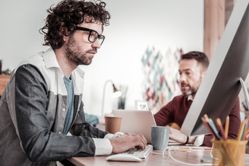 Attentive brunette man completing task on computer