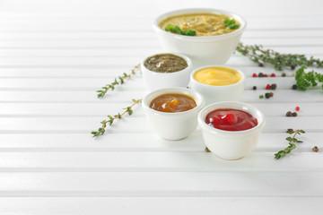 Different tasty sauces in bowls on white wooden table