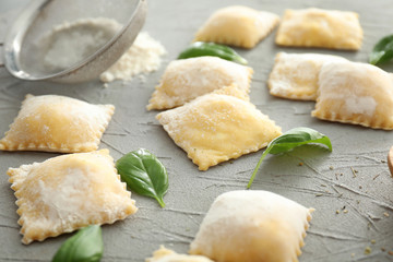 Uncooked ravioli on grey textured background