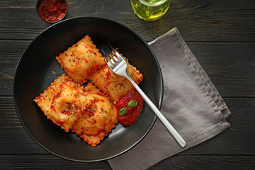 Plate with cooked ravioli on wooden table