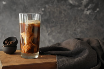 Glass of cold coffee with milk on wooden board