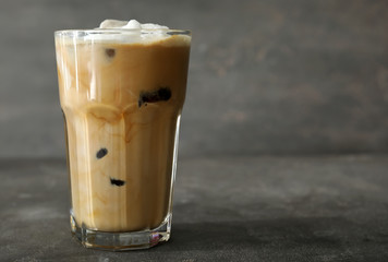 Glass of cold coffee with milk on grey table