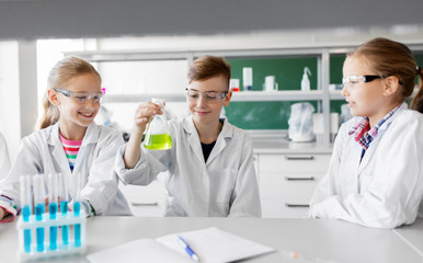 education, science and children concept - kids with test tubes studying chemistry at school...