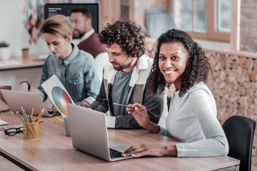 Pretty international girl sitting near her colleagues
