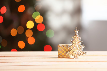 Gift box on wooden table against blurred Christmas tree