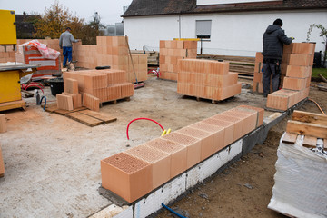 Maurer bauen eine Ziegelmauer an einem Rohbau