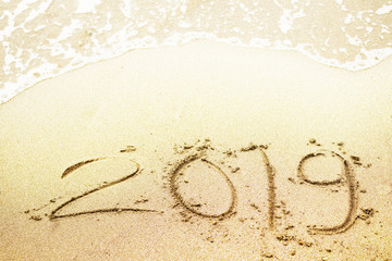 Lettering new year 2019 on sand on the sea beach, toned.