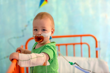 little boy in hospital bed with iv infusions and oxigen