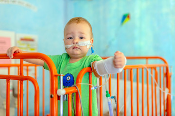 little boy in hospital bed with iv infusions and oxigen