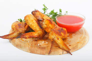 Grilled chicken wings with ketchup and spices  on a wooden board. Traditional food buffalo, white background.