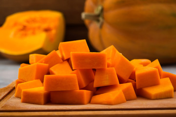 Cooking pumpkin. Sliced pieces of flesh. Kitchen chopping Board. Wooden background. Vegetarian food.