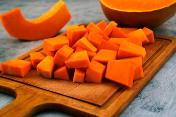 Pieces of pumpkin on the Board. Orange flesh of ripe fruit. Vegetarian food. Raw vegetables. Preparation of dishes.