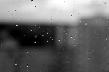Rain drops on window with blured background in black and white.