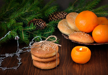 Christmas homemade cookies, fir branches, tangerines and a candle on a wooden background.