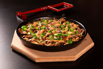 Shitake mushrooms in iron pan in a black background.