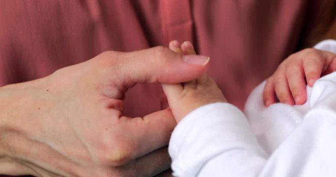Close Up Of Loving Mother Holding Hand Of Newborn Baby Son