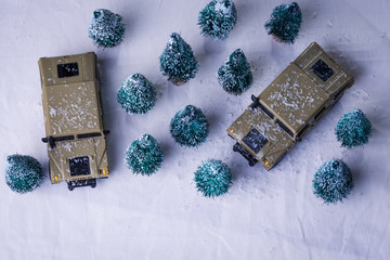 Toy military vehicles amid tory evergreen trees in winter © Arthur