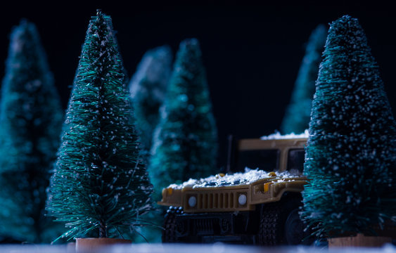 Toy military vehicle among toy christmas trees in winter