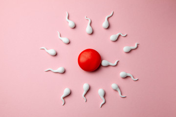 Active sperm cells swim to the egg on a pink background. The concept of pregnancy, fertilization of...
