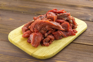 Meat beef cut into pieces lies on a wooden Board