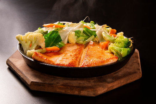 delicious Teppanyaki Salmon food with chopsticks and vegetable in the iron pan.