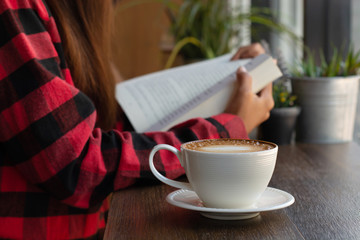 Woman is reading a book in a coffee shop