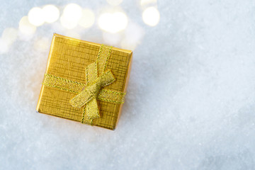 White christmas. - golden gift box in snow with bokeh lights