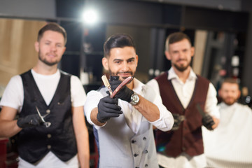Selective focus of straight razor in hands of stylish barber