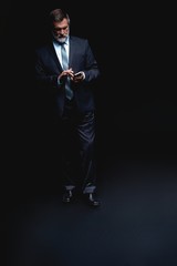 Full length portrait of Mature business man wearing formal suit standing on black background.