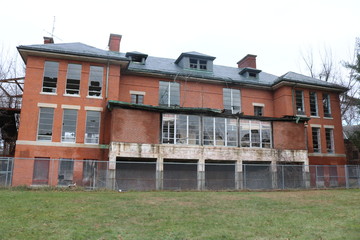 Abandoned and boarded up brick mental asylum hospital building exterior