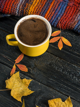 Composition with a mug of hot coffee and dry leaves on a wooden table